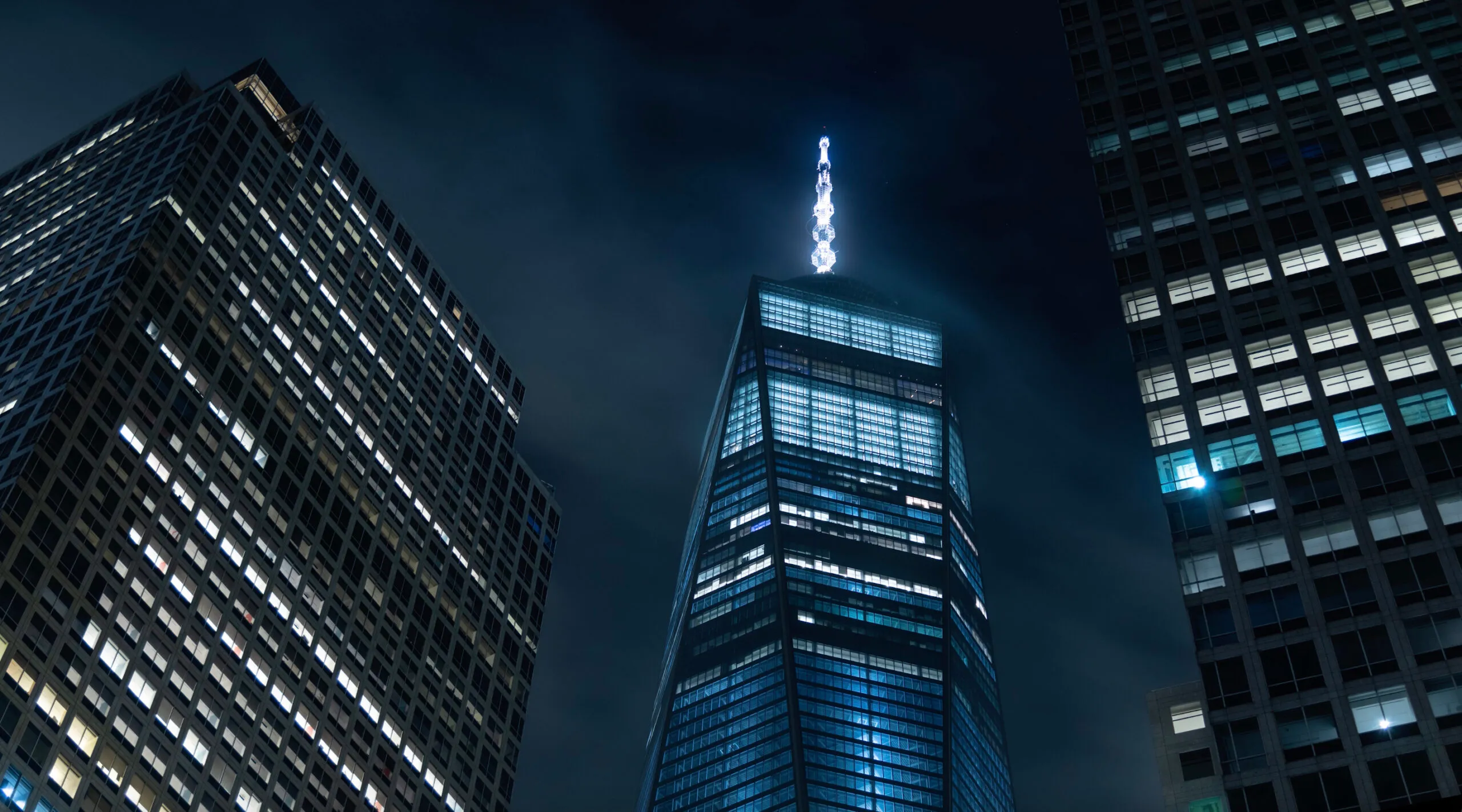 Night view of One World Trade Center between office towers
